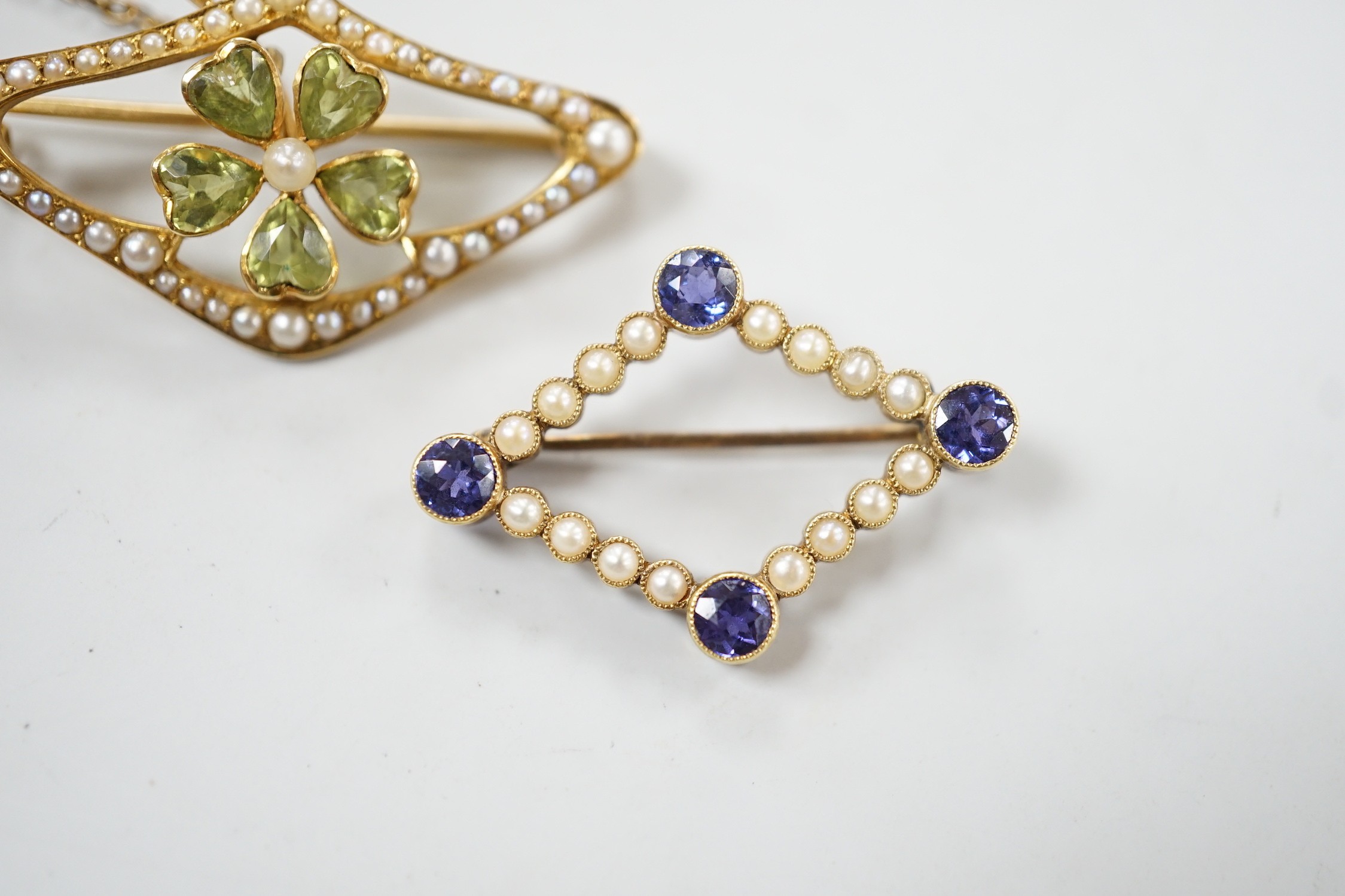 An Edwardian 15ct, peridot and seed pearl set brooch, 36mm and a similar sapphire and split pearl set brooch, gross weight 8.1 grams.